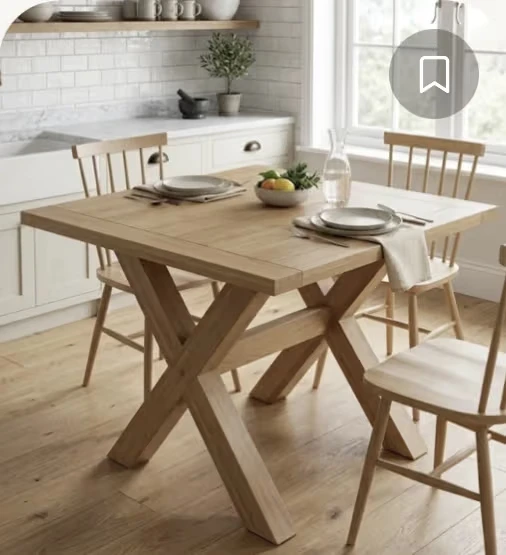 A square natural-wood dining table with an X-shaped base.